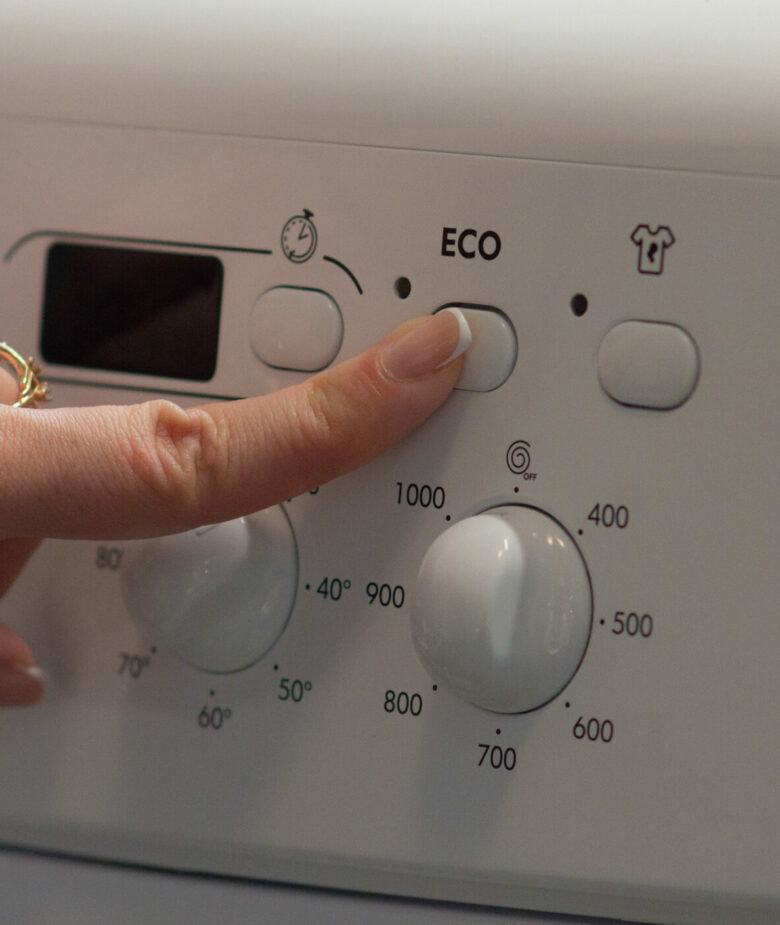 The girl sets the ekonomic mode in the washing machine